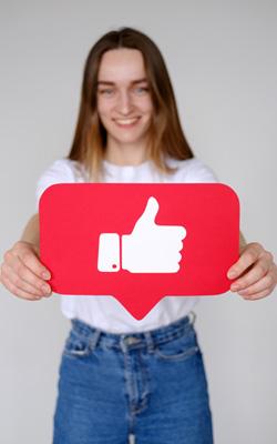 Young woman holding social media like button